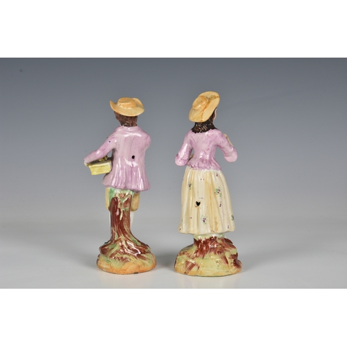 65 - A 19th century pair of Staffordshire figures, of a young man carrying a basket of fruit and young wo... 