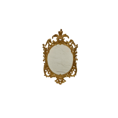 763 - A mid-Georgian carved giltwood oval mirror, with pierced foliate cresting, the pierced scrolling sur... 