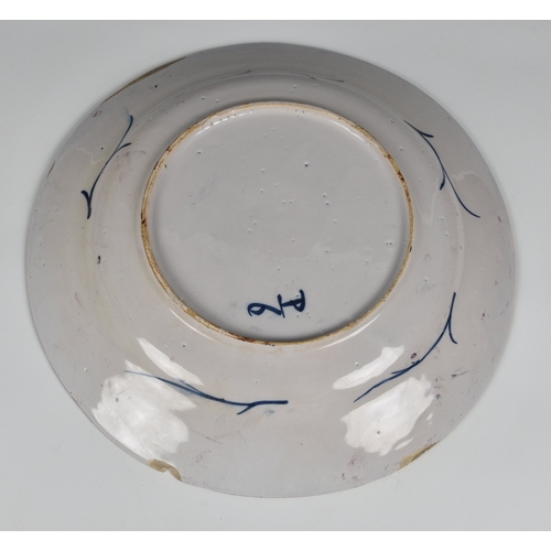 23 - A Continental, 18th century, faience dished platter,  stylised floral decoration on plum coloured gr... 