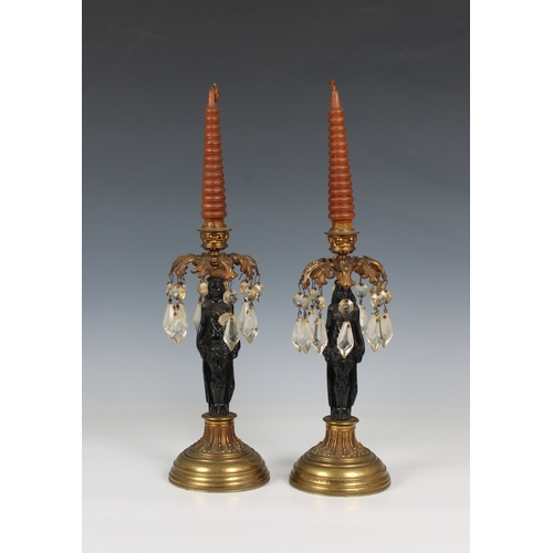 1120 - A pair of figural cast iron and gilt metal Egyptian Revival lustre candlesticks the painted black fi... 