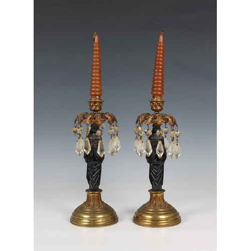 1120 - A pair of figural cast iron and gilt metal Egyptian Revival lustre candlesticks the painted black fi... 