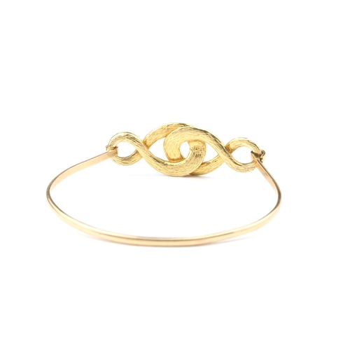 136 - An 18ct yellow gold and diamond bangle unmarked, tests as 18ct gold, the open, interlaced scrollwork... 