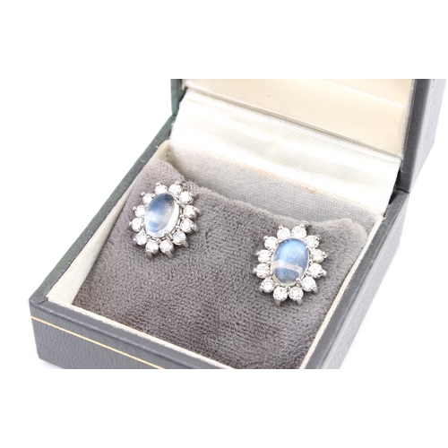 289 - A pair of 18ct white gold, moonstone and diamond cluster earrings the oval cabochon moonstones withi... 