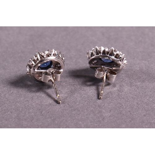 309 - A pair of circular diamond and sapphire cluster earrings set in 18ct. white gold.