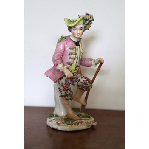 369 - A Sitzendorf porcelain figure of a boy gardener with one foot on his spade, wearing a yellow waistco... 