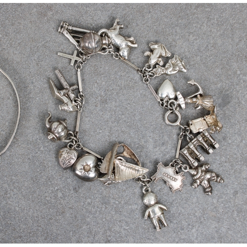 40 - A silver charm bracelet having twenty charms, comprising a Guernsey can, cat, frog, sailing boat etc... 