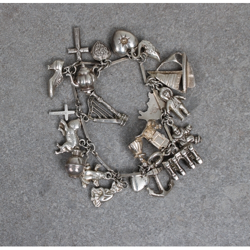 40 - A silver charm bracelet having twenty charms, comprising a Guernsey can, cat, frog, sailing boat etc... 