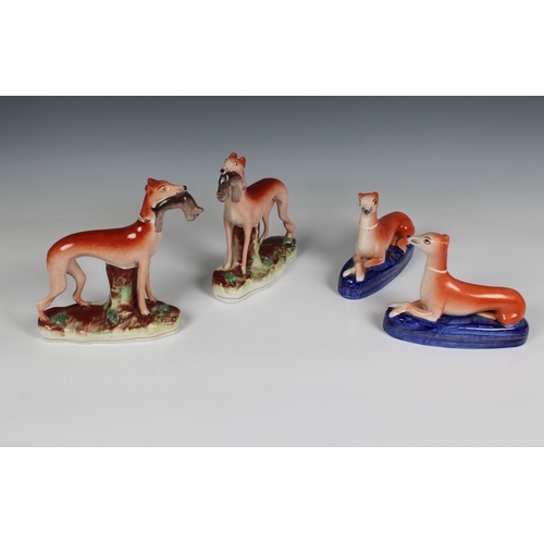 405 - Two pairs of Staffordshire pottery greyhounds two with rabbits in their mouths, 5½in. (14cm.) high &... 