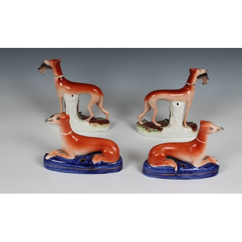 405 - Two pairs of Staffordshire pottery greyhounds two with rabbits in their mouths, 5½in. (14cm.) high &... 