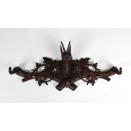 718 - A carved oak wall mounted pair of coat hooks flanking a deer's head the hooks in the form of antlers... 