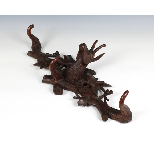 718 - A carved oak wall mounted pair of coat hooks flanking a deer's head the hooks in the form of antlers... 