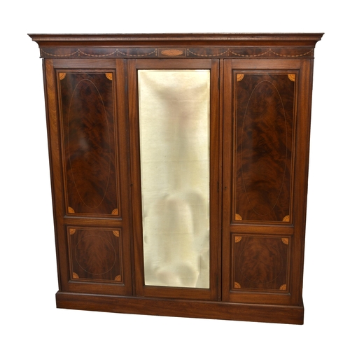 782 - An Edwardian inlaid mahogany triple wardrobe the flared cornice over inlaid swag and patera design, ... 