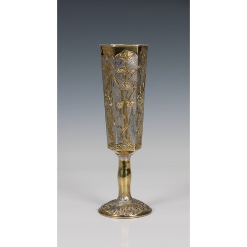 147 - A Russian silver gilt goblet of elongated hexagonal form, having raised floral and foliate decoratio... 