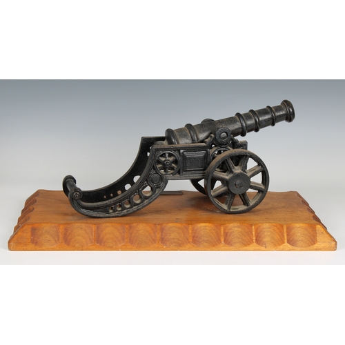 298 - A model cannon with an iron barrel and iron two wheeled gun carriage mounted on a wooden base bearin... 