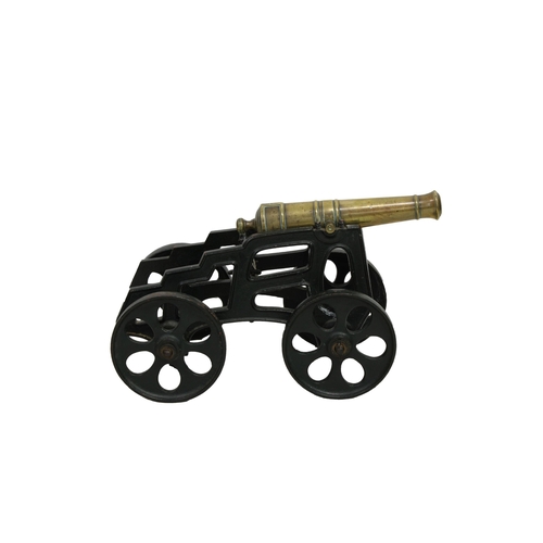 300 - A model cannon with a polished brass barrel and iron four wheeled gun carriage barrel 14½in. (37cm) ... 