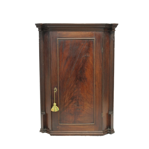 522 - A Georgian mahogany corner cupboard with dentil cornice and reeded half pilasters, a single flame ma... 