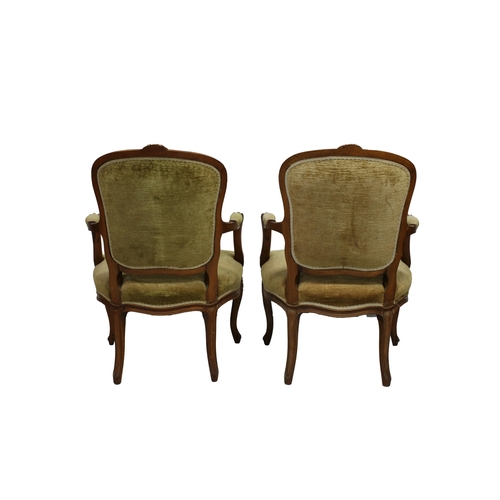 560 - A pair of French beechwood channel carved open armchairs upholstered in green velvet, with floral ca... 