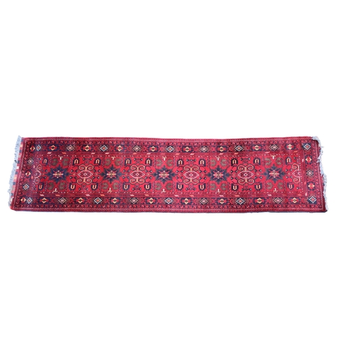 575 - A Turkmen Khal Mohammadi runner with repeating medallions and borders on a brick red ground, 32 x 12... 