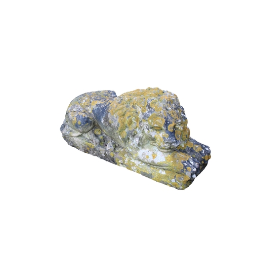 576 - A composite stone recumbent lion having aged and weathered patina.