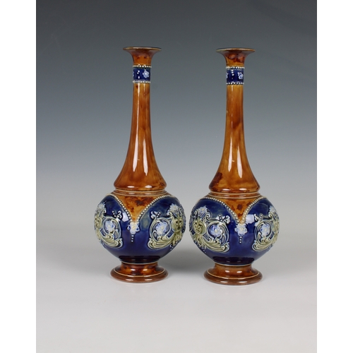 92 - A pair of Doulton Lambeth sprinkler vases the blue reserves with moulded decoration to a brown groun... 