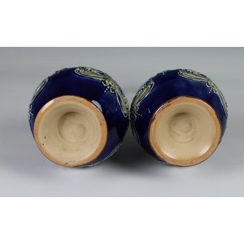 92 - A pair of Doulton Lambeth sprinkler vases the blue reserves with moulded decoration to a brown groun... 