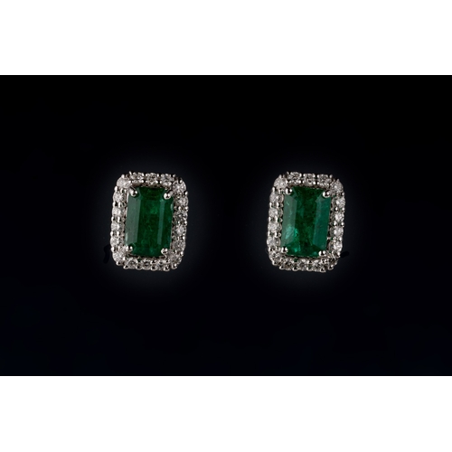 672 - A pair of emerald and diamond cluster earrings Each emerald-cut emerald claw set in a diamond surrou... 