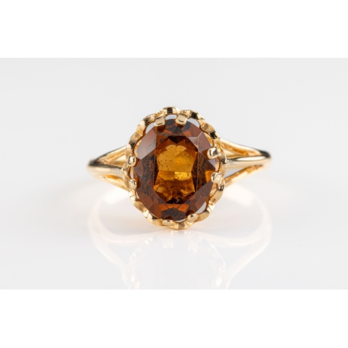 680 - A 9ct yellow gold and citrine ring The oval cut dark citrine claw set to spilt shoulders and taperin... 