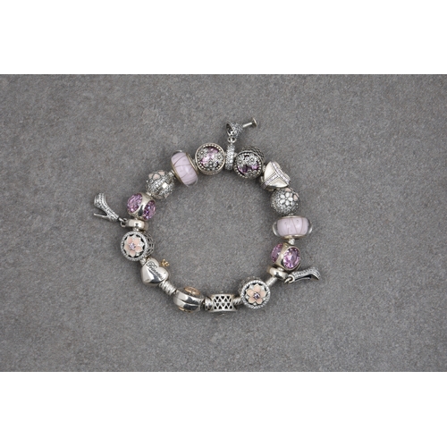 688 - A Pandora bracelet with sixteen silver charms in pink and cream tones, all set with enamel, glass or... 