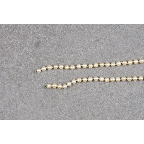 694 - A single strand cultured pearl necklace the evenly sized 7.5mm. pearls with a diamond set 14ct gold ... 