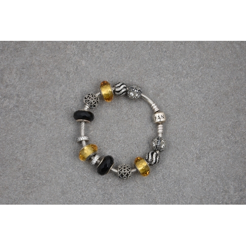 696 - A Pandora bracelet with eleven silver charms in silver, black and amber tones, most set with crystal... 