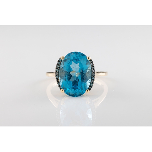 788 - A 9ct yellow gold blue topaz ring The oval cut blue topaz accentuated with blue topaz shoulders.