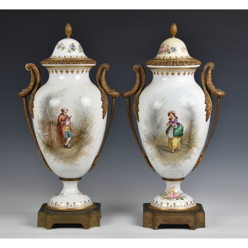 70A - A pair of Sevres style porcelain urn shaped lidded vases ormolu mounted, hand painted with elegant f... 