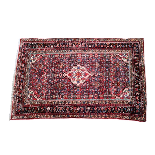 249 - A hand knotted Hamadan wool rug with a central medallion on a red ground with filler motif, flanked ... 