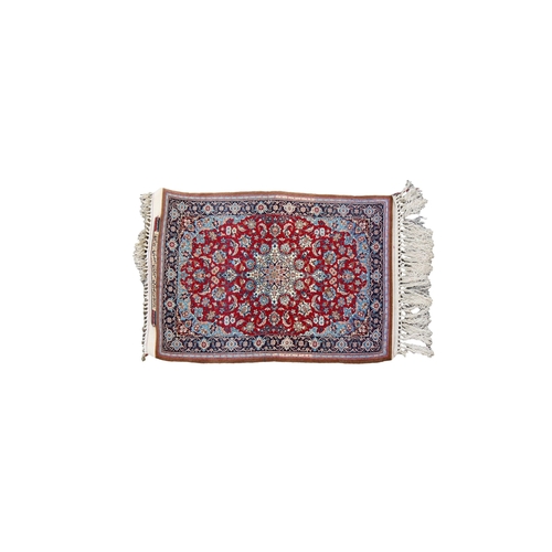 253 - A signed silk fringe Isfahan rug with a central medallion on red ground with floral spandrels and bo... 