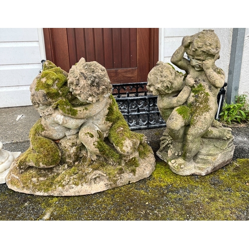 263 - Two composite stone garden statues of cavorting cherubs 24in. (61cm.) and 19½in. (49.5cm.) high.