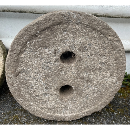 275 - A granite plinth or mill stone of thick circular form, having twin circular holes, the back with cir... 