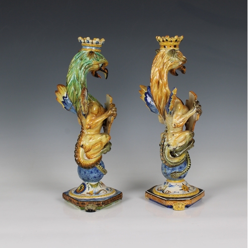 72 - A near pair of Italian Cantagalli majolica griffin form candlesticks the crowned griffins holding sh... 