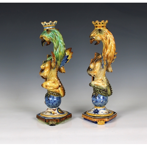 72 - A near pair of Italian Cantagalli majolica griffin form candlesticks the crowned griffins holding sh... 