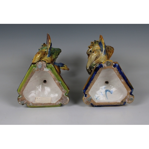 72 - A near pair of Italian Cantagalli majolica griffin form candlesticks the crowned griffins holding sh... 