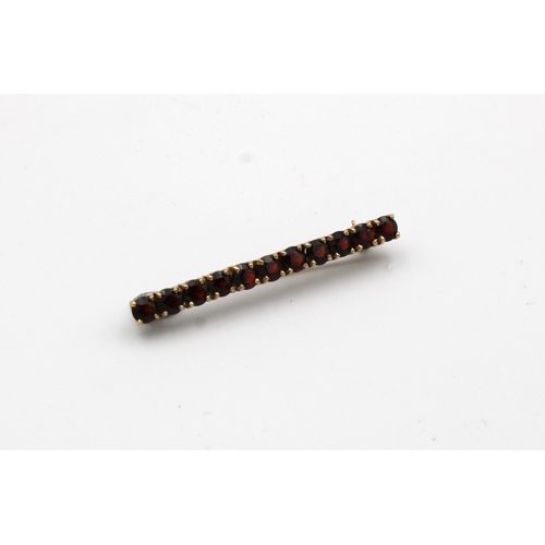 1055 - A 9ct gold garnet set bar brooch.