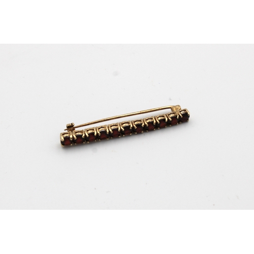 1055 - A 9ct gold garnet set bar brooch.