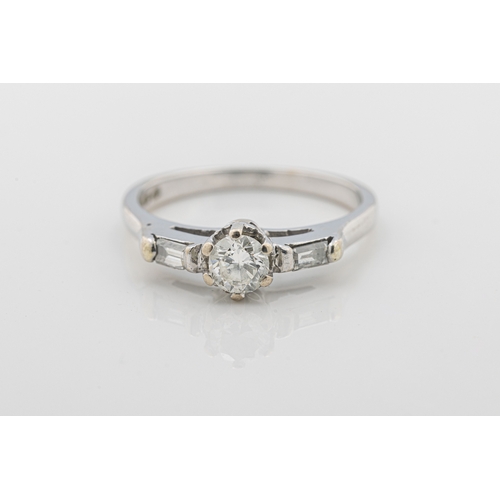 1064 - A diamond ring in 18ct white gold, claw-set with a brilliant-cut diamond and baguette-cut shoulders,... 