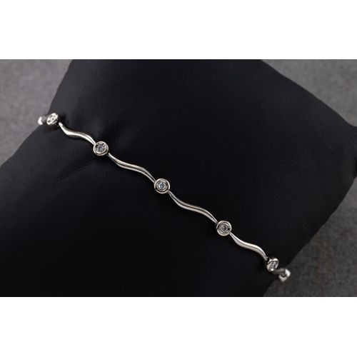 1261 - A diamond bracelet in 18ct white gold, with wave-links interspersed with ten bezel-set brilliant-cut... 