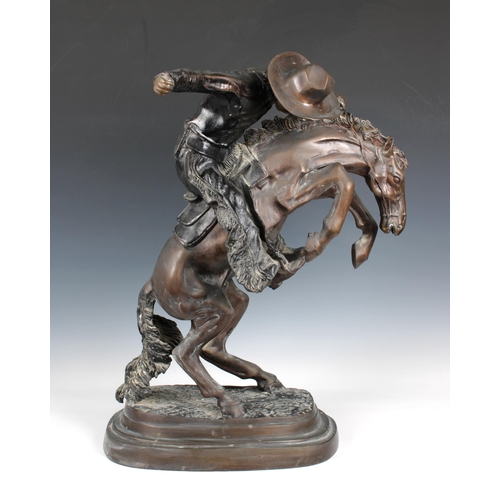 1400 - A large bronze figure of a cowboy on horseback, in the manner of Frederick Remington modelled as 'Th... 