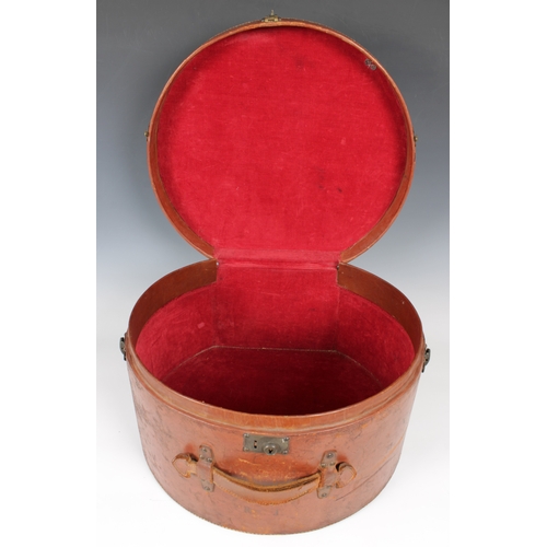 1450 - A large leather hat box or circular form with lock and carry handle, the hinged cover opening to rev... 