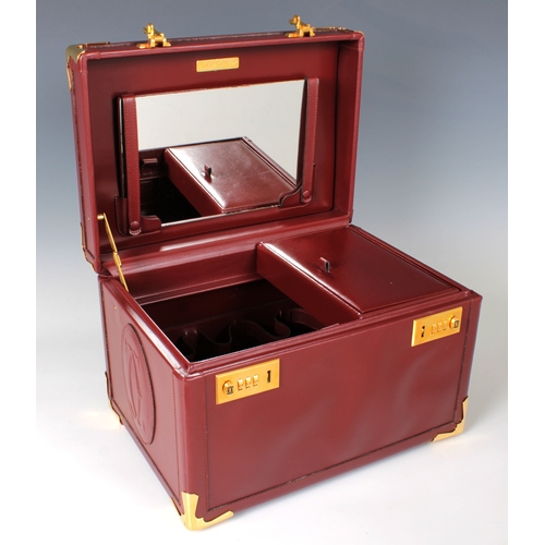 1495 - A Cartier burgundy leather vanity case with gilt metal fittings, combination locks, vanity mirror an... 