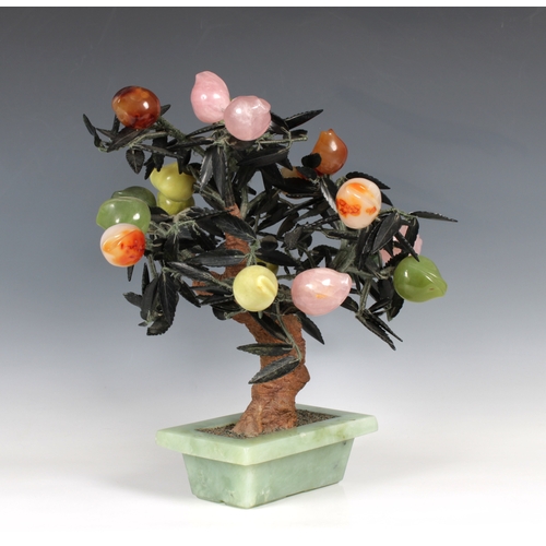 728 - An Oriental carved hardstone tree centrepiece bearing various coloured fruit, 42cm. high.