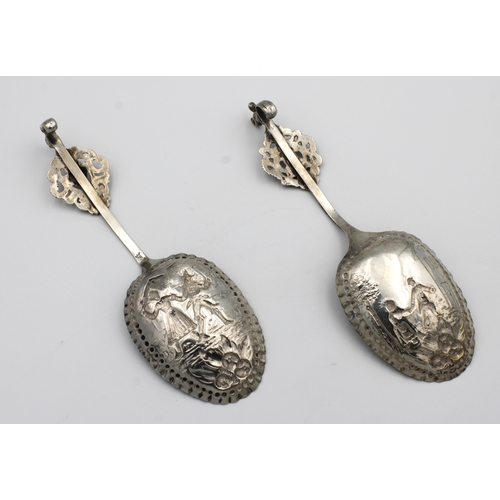 1039 - A pair of large Dutch silver wine or fruit spoons repousse decorated with figures in town scenes, sq... 