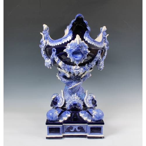 33 - An impressive ceramic blue glazed jardiniere of navette form, having dolphin head lugs and supported... 