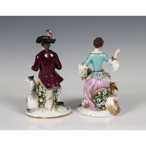 60 - A pair of German porcelain figures of an elegantly dressed couple the man with a hound and the woman... 